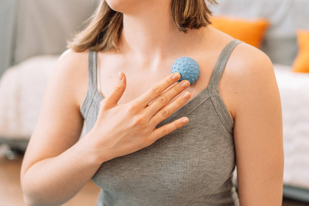 Girl kneads the pectoral muscles with myo fascial release ball. - Photo, Image