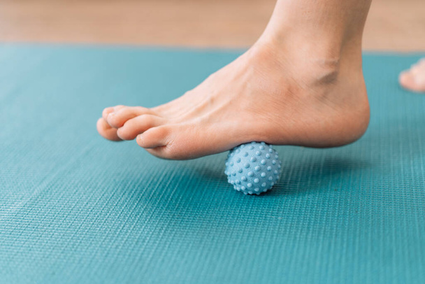 Lady kneading her feet with myo fascial release ball. - Photo, Image