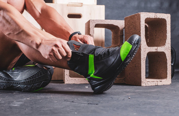 Сильный мужчина надевает обувь в спортзале - Фото, изображение