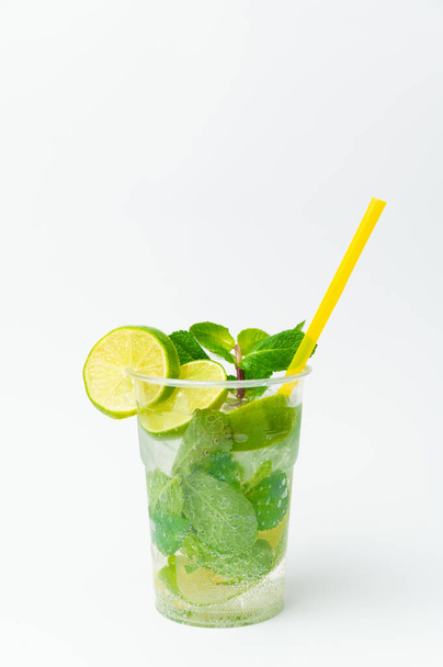 Vertical isolated shot of a fresh lime lemonade in a to go plastic glass with mint. - Fotó, kép