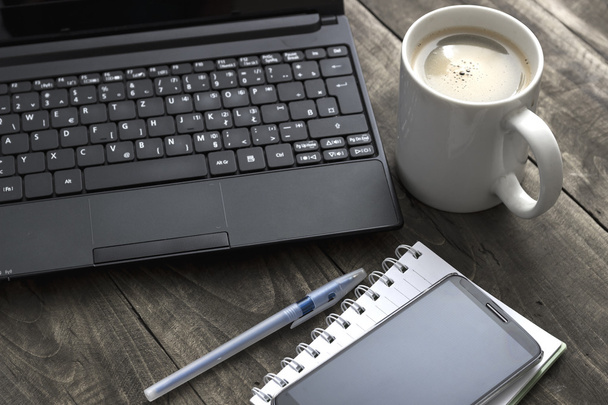 Scrivania da ufficio con caffè, blocco note e laptop
. - Foto, immagini