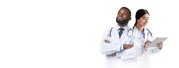 Medical Background With Two Doctors In Uniform Standing Isolated Over White Background, Male And Female Physicians Standing Over Light Backdrop, Woman Holding Digital Tablet, Collage, Copy Space - Photo, Image