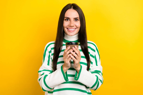 Photo of cheerful shiny lady dressed striped pullover enjoying hot coffee isolated yellow color background. - 写真・画像