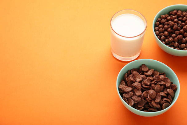 Bowl with cereals and a glass of milk on orange background. Top view. Space for text - Fotó, kép