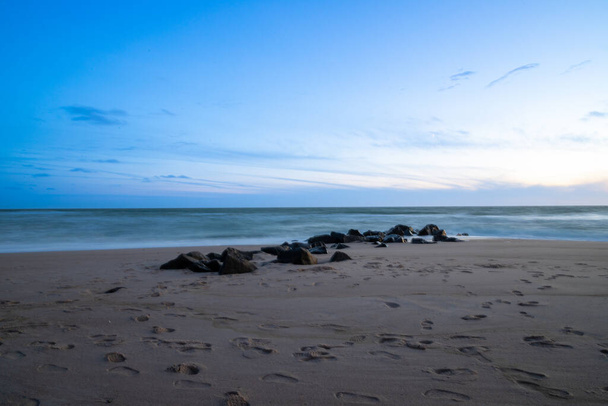 Lange Belichtung am Meer mit Felsen im Sand, blaue Stunde. Hochwertiges Foto - Foto, Bild