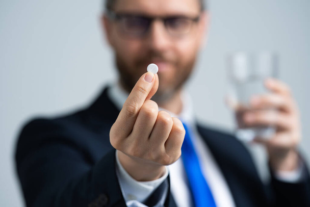 Pill close up. Medicine pill from headache migraine. Headache, tiredness and stress. Business man in suit is hold pill. Deadline and stressed job - Foto, Imagen