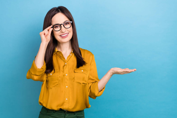 Photo of young smile accountant girl business company new ophthalmology brand company glasses hold palm mockup isolated on blue color background. - Fotó, kép