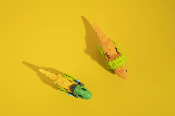 Spielzeug-Dinosaurier aus Plastik auf gelbem Hintergrund. Draufsicht, flache Lage. - Foto, Bild