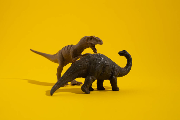 Plastic dinosaur toy on yellow background. - Fotoğraf, Görsel