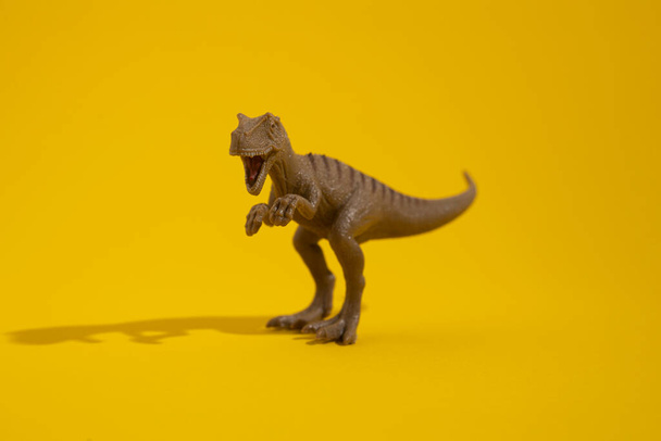 Plastic dinosaur toy on yellow background. - Fotoğraf, Görsel