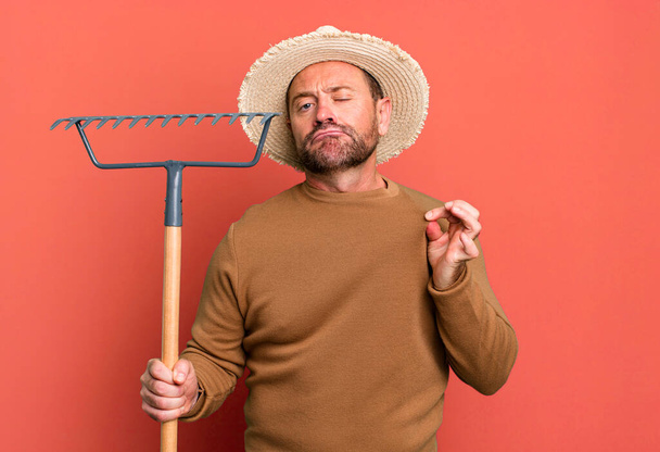 middle age man looking arrogant, successful, positive and proud. farmer with a rake - Foto, Bild
