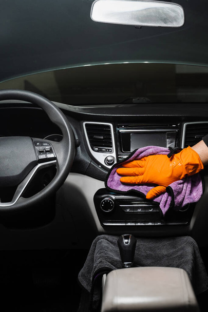 Hand car interior drying with microfiber of dashboard and multimedia in detailing auto service. Cleaner worker dry car interior. Final stage of detailing dry cleaning - Фото, зображення