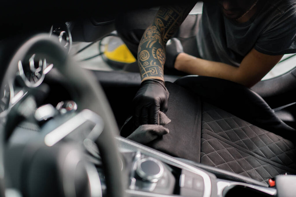 Cleaning the car interior with a brush A car detailing worker cleaning car interior and seat with brush and foam the concept of car detailing - 写真・画像