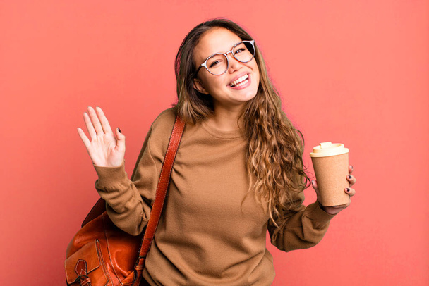 hispanic pretty woman smiling happily, waving hand, welcoming and greeting you. take away coffee concept - Foto, Bild