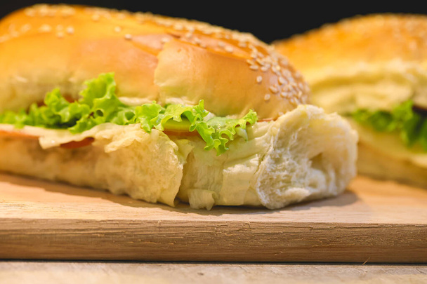 Sandwiches de pan con semillas de sésamo, pechuga de pavo, queso mozzarella, lechuga, tomates y mayonesa sazonada  - Foto, Imagen