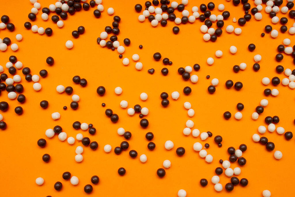 white and black chocolate balls on an orange background - Zdjęcie, obraz