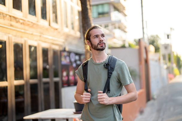 Sırt çantalı genç adam sokakta yürüyor. - Fotoğraf, Görsel