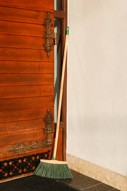 The broom is standing in front of the door. Cleaning time - Foto, Bild