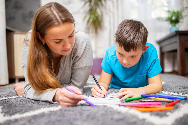 Gelukkig gezin spelen samen thuis op de vloer. Moeder en haar zoon schilderen samen - Foto, afbeelding