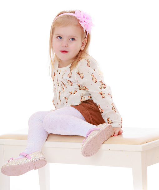 Beautiful little girl sitting on white banquettes. - Фото, изображение