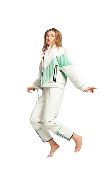 A girl in a fashionable light tracksuit for a walk poses on a white background barefoot, clothing advertising, street style, comfortable stylish casual wear. - Photo, Image