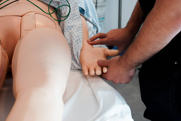 Przez dwa dni pielęgniarki i pielęgniarki odbywają szkolenie w Szkole Medycznej Montpellier na temat procedur i resuscytacji w nagłych wypadkach. Sesja symulacyjna na manekinie Simmana. Pobieranie pulsu. - Zdjęcie, obraz