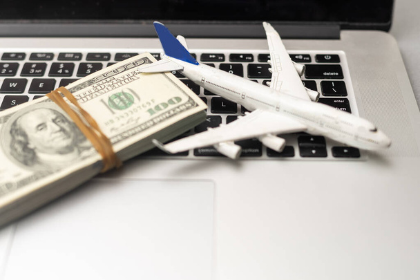 avion, argent et clavier. achat en ligne de billets d'avion sur une table en bois gris. - Photo, image