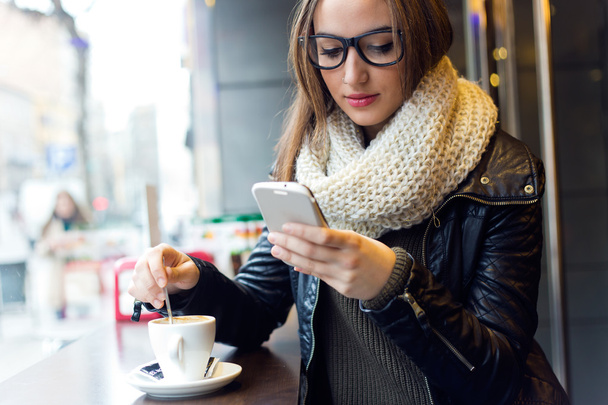 Beautiful girl using her mobile phone in cafe. - Foto, Bild