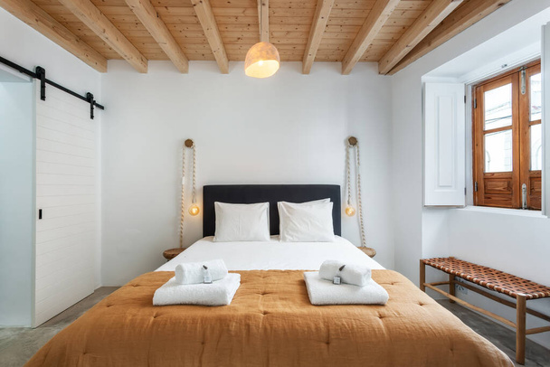 Traditional modern Iberian bedroom with wooden ceiling and clean towels and linens. High quality photo - Photo, image