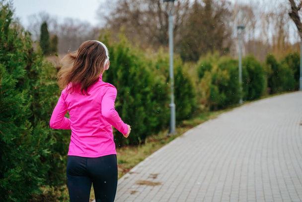 Uma atleta jogging feminino com seu smartphone e fones de ouvido, mantendo-se motivada e energizada durante o treinamento para sua próxima grande corrida. - Foto, Imagem