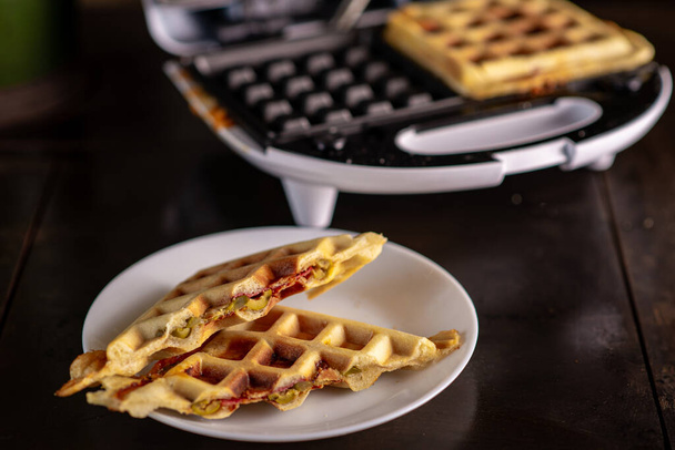 Pizza waffles, piffle. Waffles stuffed with sausage, cheese, tomatoes on a plate. - Foto, Imagem