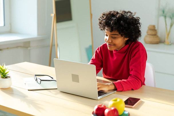 Африканська дівчина з Америки, користуючись ноутбуком, спілкується вдома. Молода жінка проводить віртуальну конференцію онлайн-дзвінків. Вчитися вдома, віддалений учитель. - Фото, зображення
