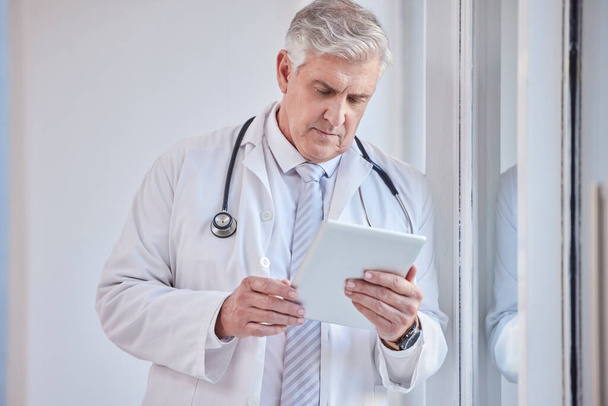 Doctor, tablet and senior man in hospital for research, telehealth or online consultation. Healthcare, technology and elderly medical professional with touch screen for wellness app in health clinic - Photo, Image