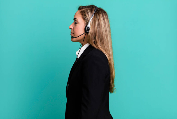 pretty blonde woman on profile view thinking, imagining or daydreaming. telemarketing concept - Foto, Imagen