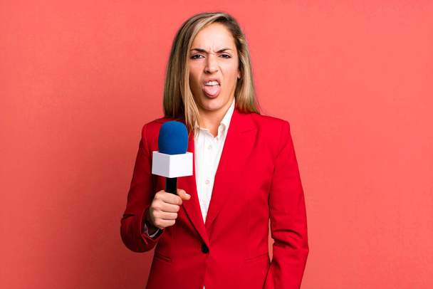 pretty blonde woman feeling disgusted and irritated and tongue out. presenter with a microphone concept - Foto, imagen