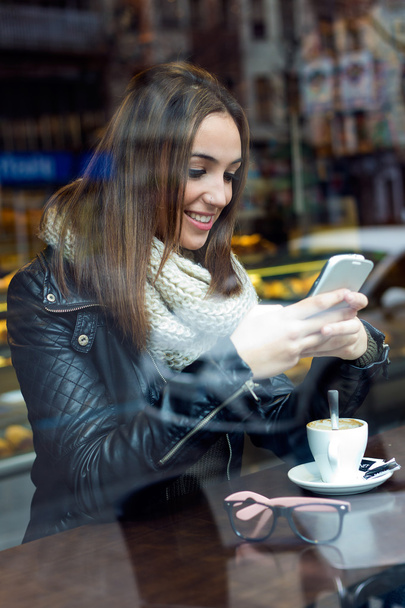 Красива дівчина використовує свій мобільний телефон в кафе
. - Фото, зображення