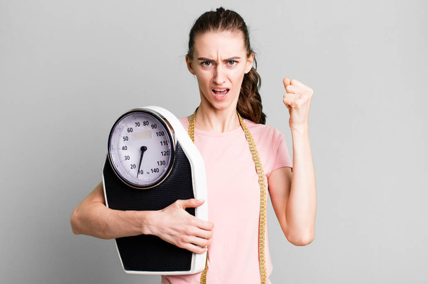 young pretty woman shouting aggressively with an angry expression. fitness and diet concept - Foto, Bild