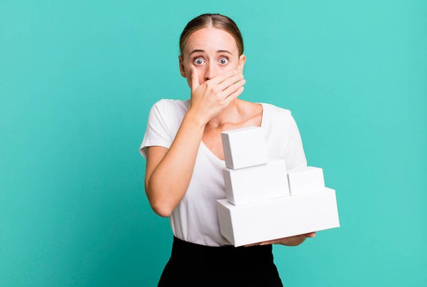 caucasian pretty woman covering mouth with hands with a shocked with white boxes packages - Fotó, kép