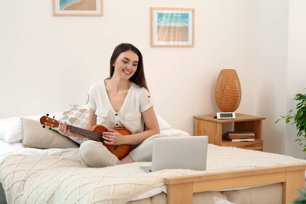 Frau lernt Ukulele mit Online-Musikkurs zu Hause. Raum für Text - Foto, Bild
