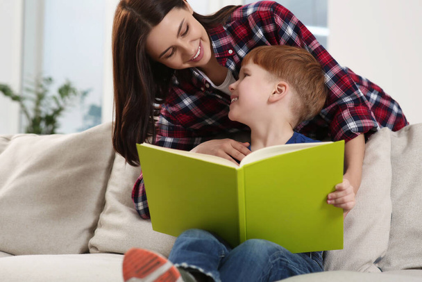 Happy mother reading book with her child at home - Photo, image