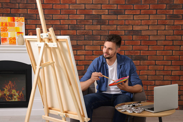 Мужчина учится рисовать с помощью онлайн-курса на ноутбуке дома. Время для хобби - Фото, изображение