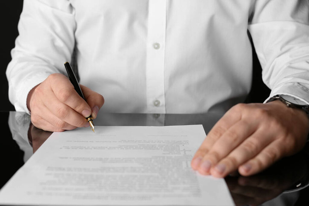 Notary signing document at black table, closeup - Φωτογραφία, εικόνα