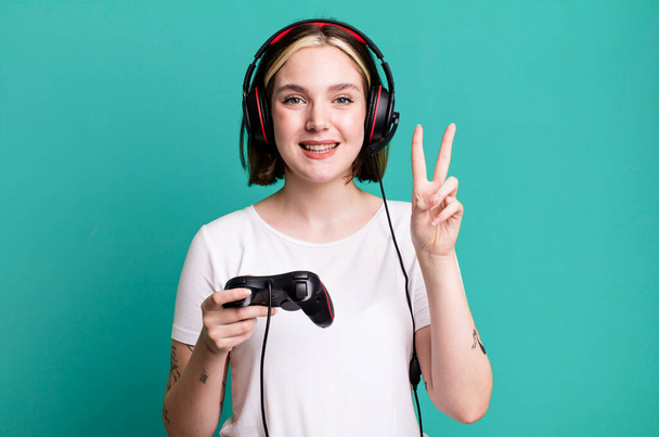young pretty woman smiling and looking happy, gesturing victory or peace. gamer concept - Foto, imagen