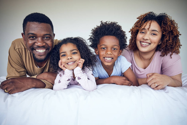 Famille noire, portrait et se détendre au lit, heureux et sourire tout en collant dans leur maison ensemble. Visage, enfants et parents se réveillent dans la chambre, couchés et se reposent, s'amusent et profitent du week-end. - Photo, image