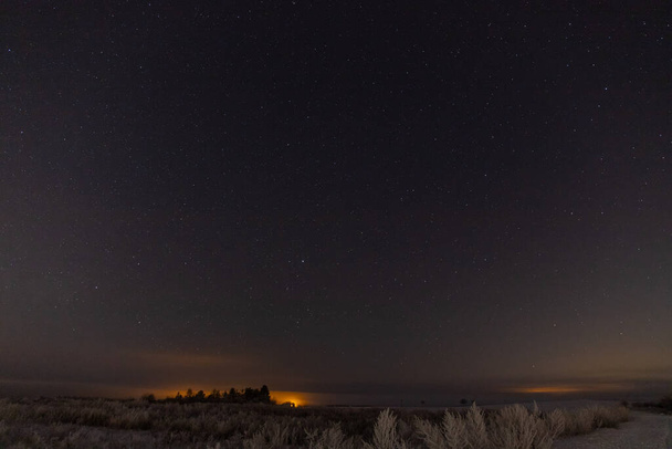 Звезды панорама ночью в снегу, оранжевые огни города на заднем плане. Высокое качество фото - Фото, изображение