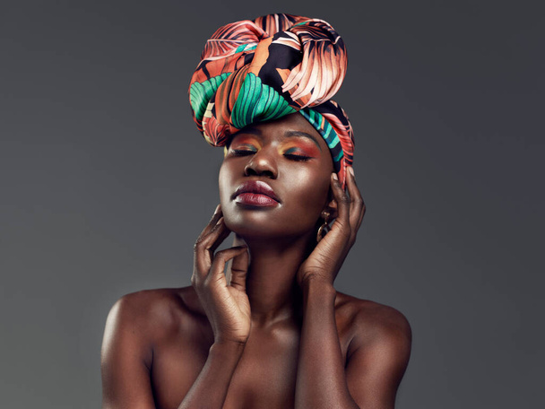 Rock your crown like the queen you are. Studio shot of a beautiful young woman wearing a traditional African head wrap against a grey background - Photo, image