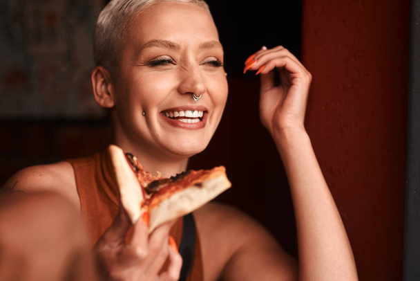 A pizza boldog étel. Egy fiatal nő pizzát eszik egy kávézóban. - Fotó, kép