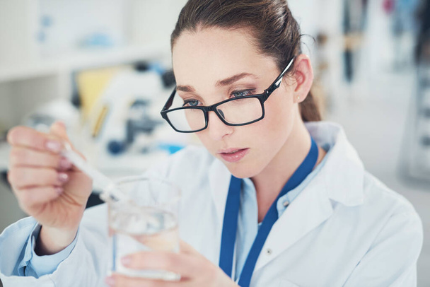 Yeni bir şey keşfettim. Odaklanmış genç bir kadın bilim adamı kimyasalları laboratuvarda masalarında karıştırıyor. - Fotoğraf, Görsel