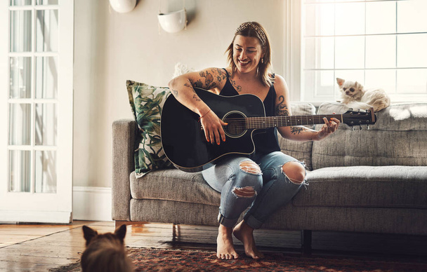 Гітаристи живуть таким добрим життям. молода жінка грає на гітарі в розслабляючий день вдома
 - Фото, зображення