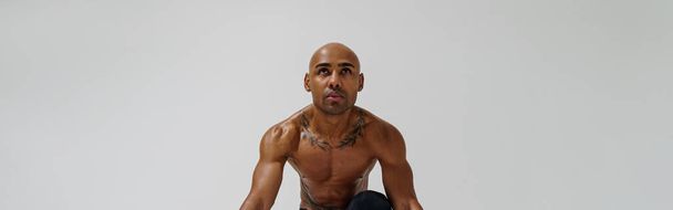 Sportsman with naked torso is warming up on white studio background - Фото, изображение
